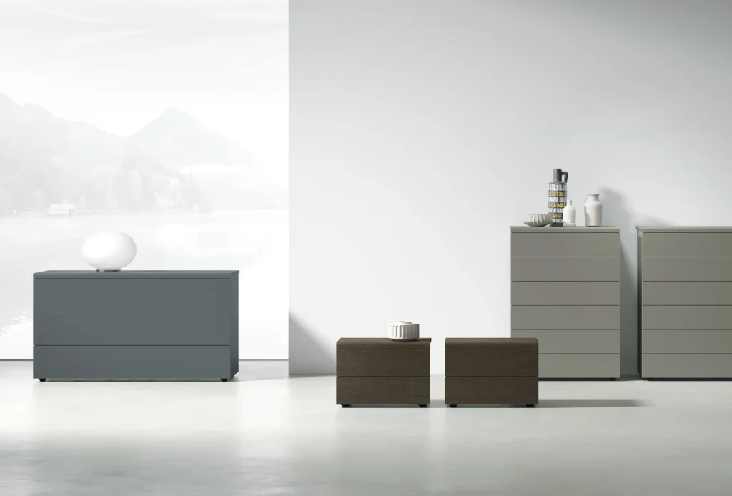 Linea contenitori Cooper di Tomasella Contract: comò in laccato opaco Ghiaccio 178, comodini in Rovere Moka, settimanali in laccato Arena 178. Design curvilineo vintage 2024.